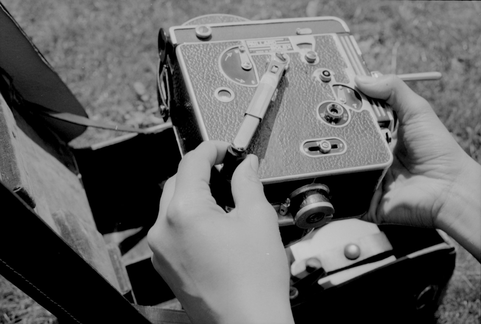 black and white image of hand winding the handle on a 16mm camera