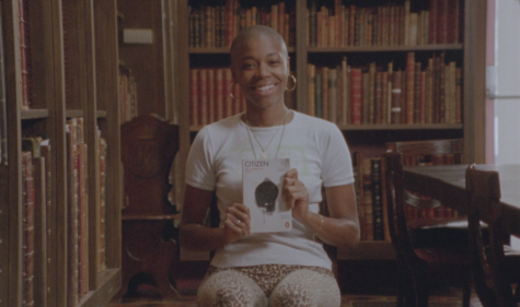 A person sitting with a bright smile holding a book, Citizen by Claudia Rankine