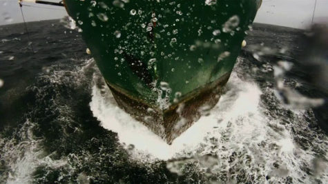 The front of a ship racing across the ocean.