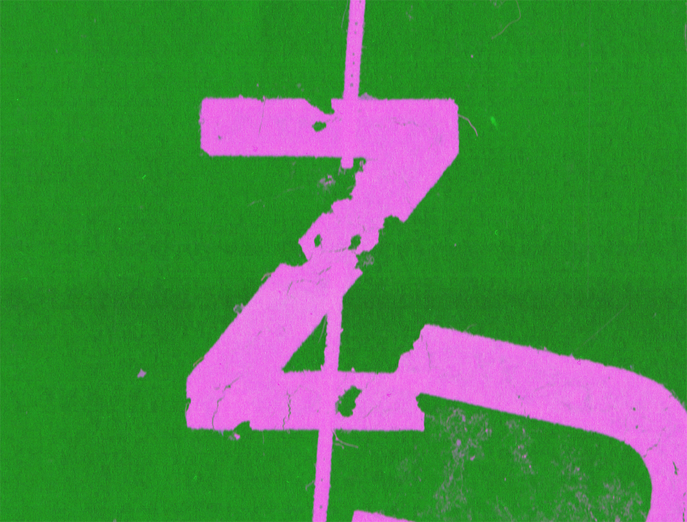 On a green background is a letter Z in fluorescent pink, ragged and torn.