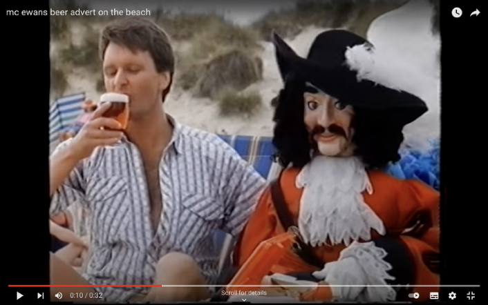 image from McEwans Advert. A man is drinking a glass of beer, next to him is a puppet cavalier, an embodiment of the McEwans logo