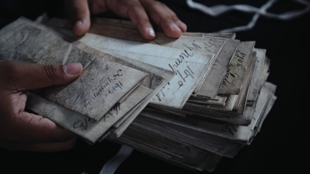 close up of hands carefully going through a stack of old letters.