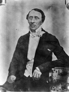a black and white images of Hans Christian Andersen. Victorian looking middle aged man wearing a black jacket and white high collared shirt