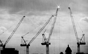 a pixellated black and white image of cranes at twilight silhouetted against the sky