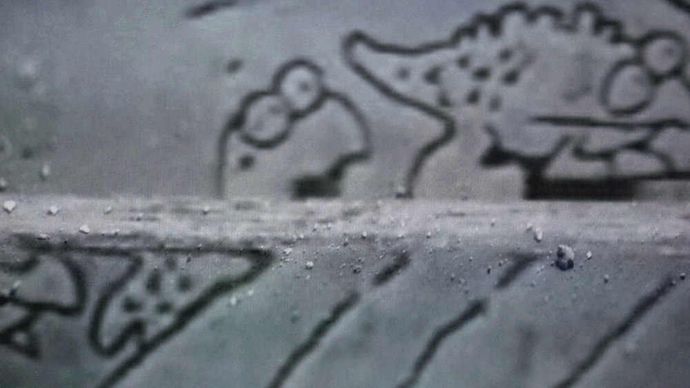 close up of a tv screen that shows a blurry illustrations of animal figures on grey surfaces which is horizontally cut by crumbled concrete like materials 