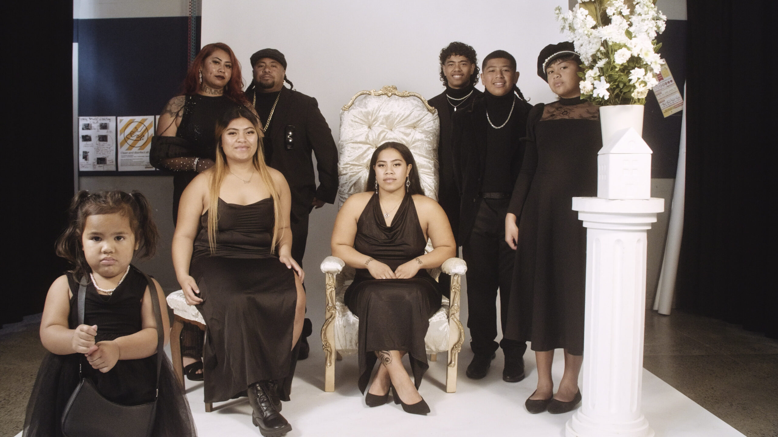 A group of people all in black dress and suits posing for a family photo in a photography studio.