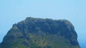 an image of a green verdant rocky hill against a blue sky