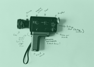 Black super 8mm camera on sheet paper with pencil explanations of the different parts of the camera. The picture has a green filter.