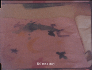 Grainy 16mm film still of a watercolour drawing of birds and moons on pinkish paper. Caption at the bottom reads: Tell me a story