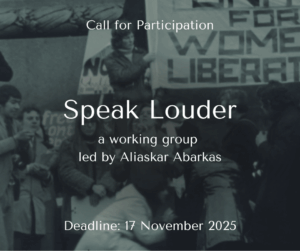 A black and white photograph of a group of protestors wrapped up warmly in winter coats, holding placards. On a raised platform above stands a person holding part of a large tapestry that reads 'Womens Liberation'.