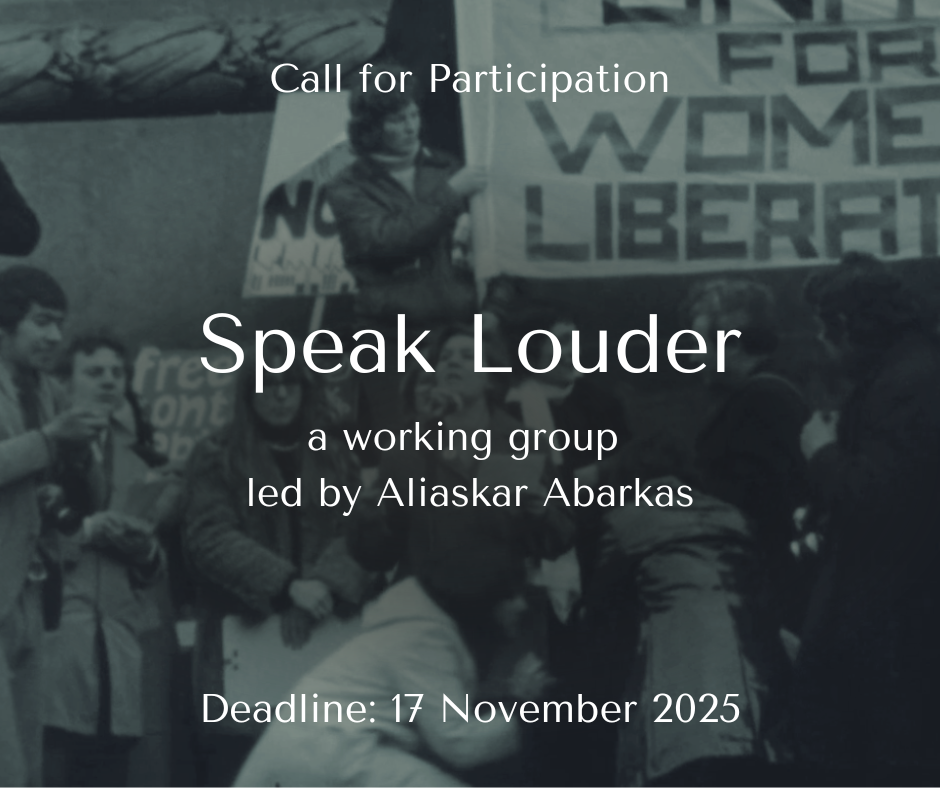 A black and white photograph of a group of protestors wrapped up warmly in winter coats, holding placards. On a raised platform above stands a person holding part of a large tapestry that reads 'Womens Liberation'.