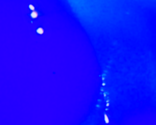A vivid, electric blue background scattered with a few glowing bubbles. The bubbles have a soft pinkish halo
