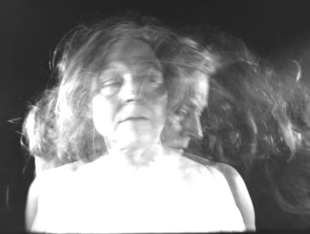 Layered Black and White Still of a Woman Standing facing the camera in multiple positions.